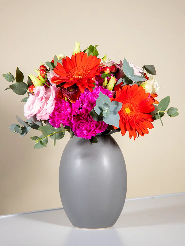 Bouquet gerbere rosse lisianthus rosa garofani fucsia in vaso grigio